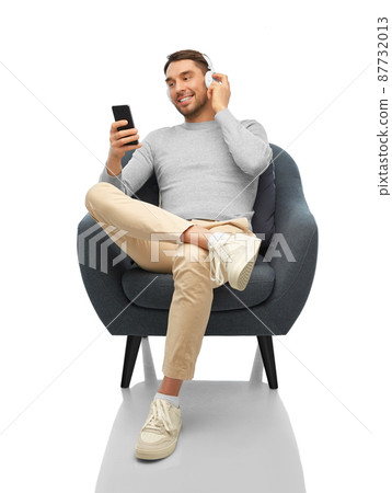 man with phone and headphones sitting in chair 87732013