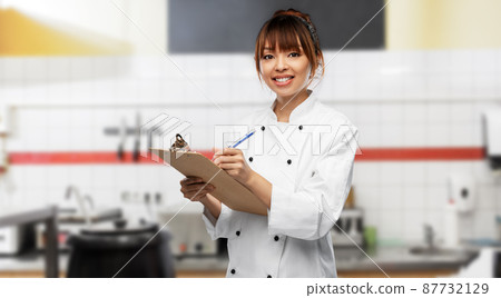 female chef with clipboard and pen on kitchen 87732129