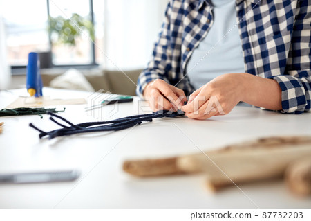 woman making macrame and knotting cords 87732203