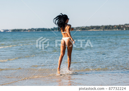 young woman in bikini swimsuit running on beach young woman in bikini swimsuit running on beach 87732224
