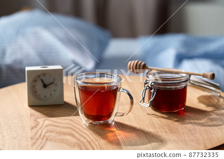 cup of tea, honey and alarm clock on table 87732335