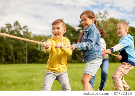 happy children playing tug-of-war game at park 87732339