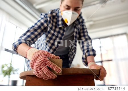woman in respirator sanding old table with sponge woman in respirator sanding old table with sponge 87732344