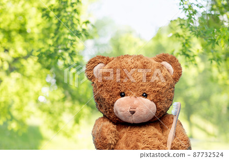 teddy bear toy with toothbrush on blue background teddy bear toy with toothbrush on blue background 87732524