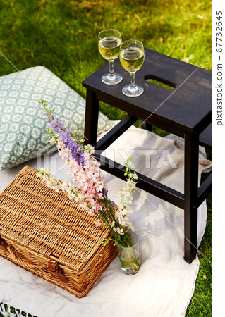 picnic basket, flowers and wine glasses at park 87732645