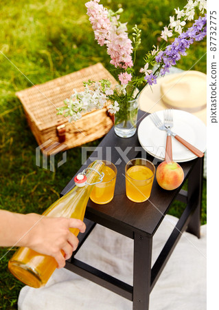 hand pouring juice to glass on picnic at park hand pouring juice to glass on picnic at park 87732775