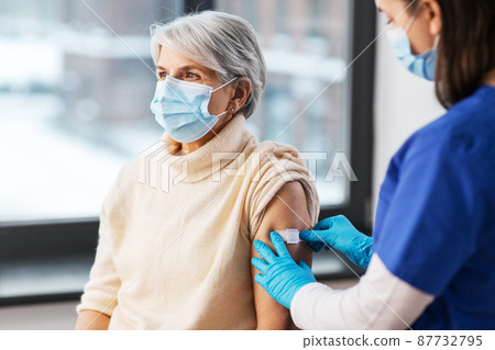 nurse applying medical patch to vaccinated woman 87732795