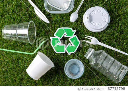 green recycling sign and plastic waste on grass 87732796
