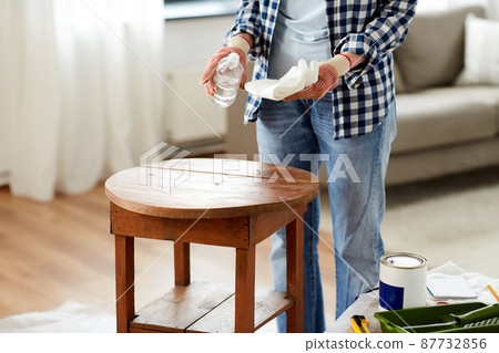 woman degreasing old table surface with solvent 87732856