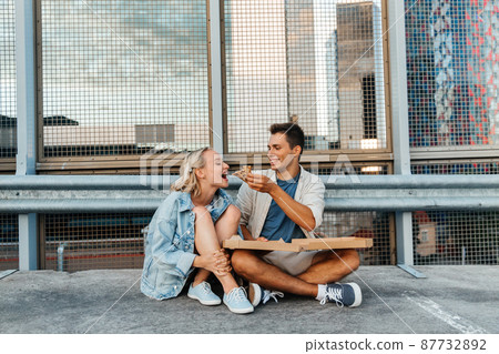 happy couple eating pizza on city roof top parking 87732892