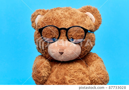 brown teddy bear toy in glasses on blue background brown teddy bear toy in glasses on blue background 87733028