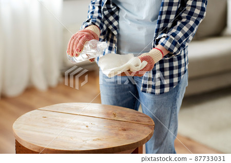 woman degreasing old table surface with solvent 87733031
