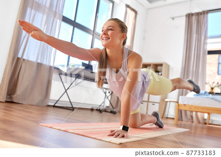 happy teenage girl exercising on yoga mat at home happy teenage girl exercising on yoga mat at home 87733183