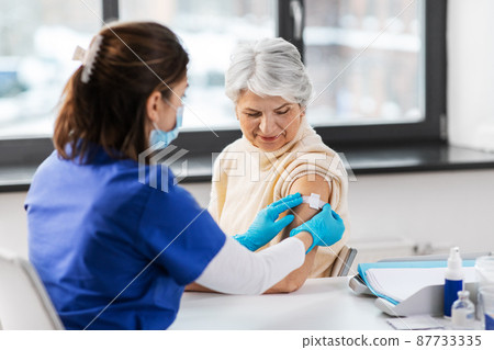 nurse applying medical patch to vaccinated woman nurse applying medical patch to vaccinated woman 87733335