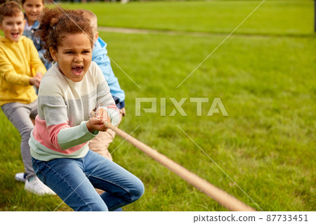 happy children playing tug-of-war game at park 87733451