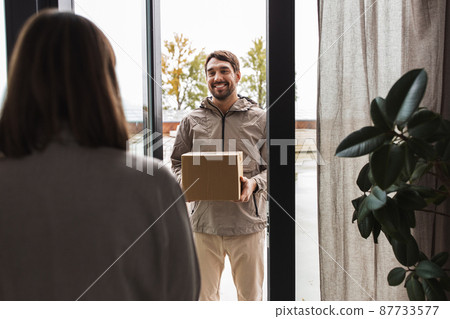 delivery man with parcel box and customer at home 87733577