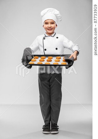 boy in chef's toque with cookies on oven tray boy in chef's toque with cookies on oven tray 87733919