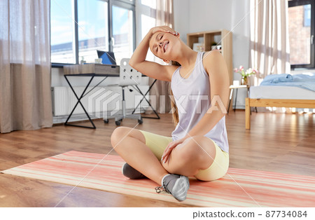 happy teenage girl exercising on yoga mat at home 87734084
