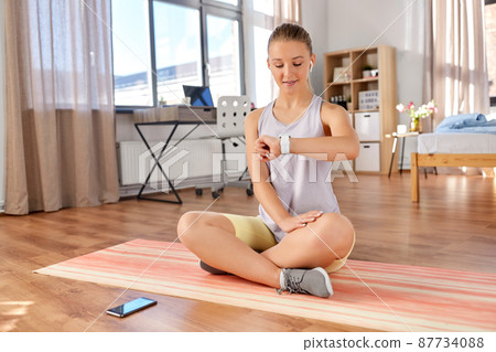 teenage girl with gadgets exercising at home teenage girl with gadgets exercising at home 87734088