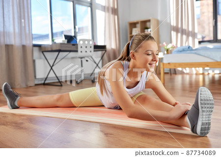 happy teenage girl exercising on yoga mat at home happy teenage girl exercising on yoga mat at home 87734089