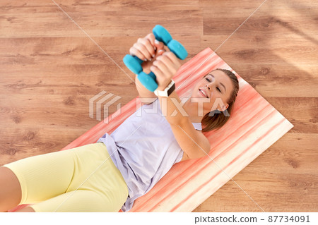 teenage girl with dumbbells exercising at home teenage girl with dumbbells exercising at home 87734091