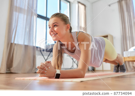 happy teenage girl exercising on yoga mat at home happy teenage girl exercising on yoga mat at home 87734094