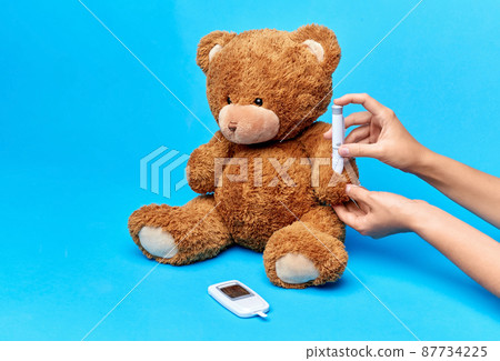 hands making insulin injection to teddy bear 87734225