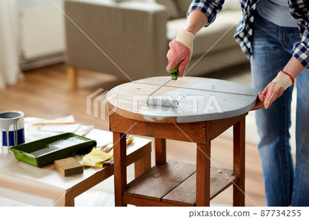 woman painting old wooden table in grey color woman painting old wooden table in grey color 87734255