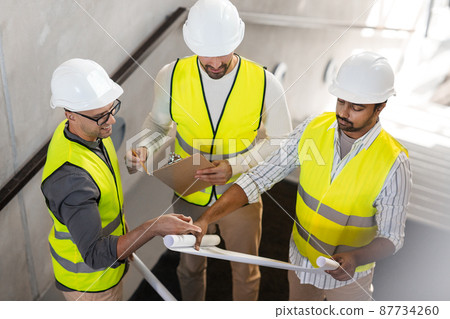 architects in helmets with blueprint at office architects in helmets with blueprint at office 87734260