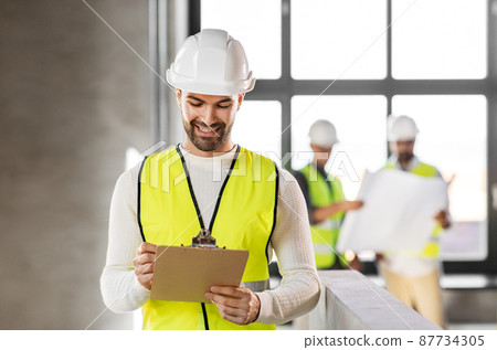 male architect in helmet with clipboard at office male architect in helmet with clipboard at office 87734305