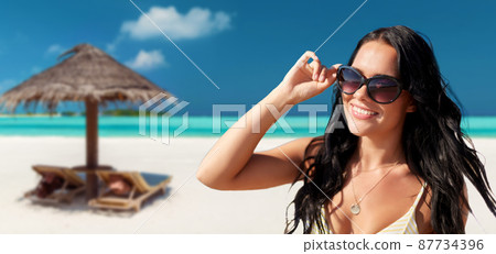 smiling young woman in sunglasses on summer beach smiling young woman in sunglasses on summer beach 87734396