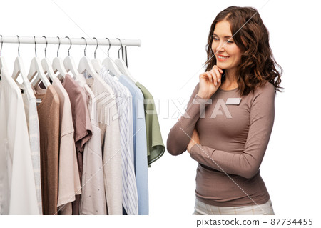 happy female shop assistant with clothes on hanger happy female shop assistant with clothes on hanger 87734455