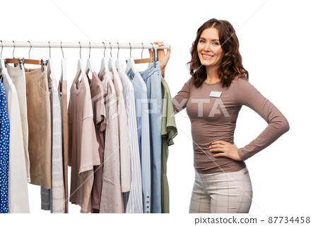 happy female shop assistant with clothes on hanger 87734458