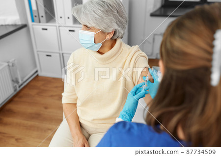 nurse with syringe making injection to woman 87734509
