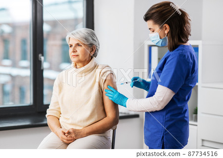 nurse with syringe making injection to woman nurse with syringe making injection to woman 87734516