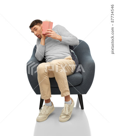scared man with popcorn sitting in chair 87734546