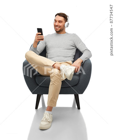 man with phone and headphones sitting in chair 87734547