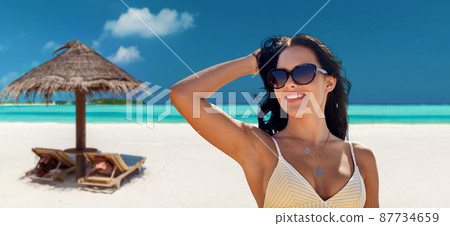 smiling young woman in sunglasses on summer beach 87734659