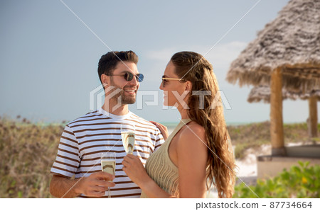 happy couple drinking champagne on summer beach happy couple drinking champagne on summer beach 87734664