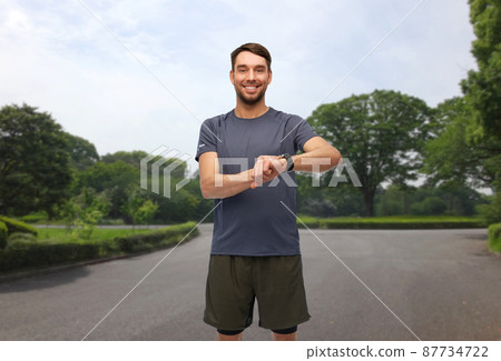 smiling man with smart watch or fitness tracker smiling man with smart watch or fitness tracker 87734722