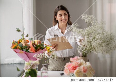 happy woman with clipboard and flowers at studio 87734817