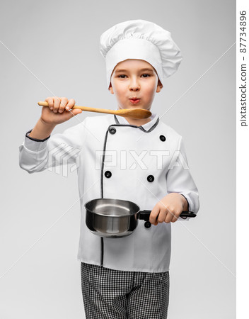 boy in chef's toque with saucepan cooking food 87734896