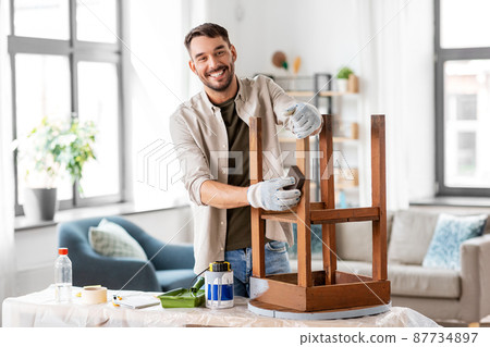man sanding old round wooden table with sponge 87734897