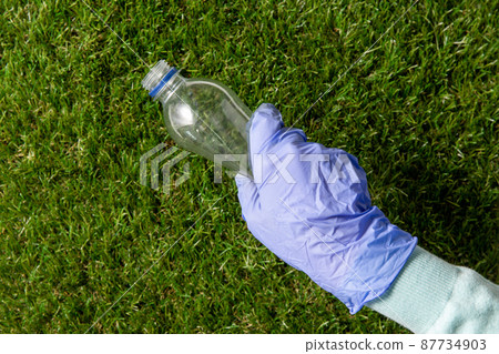 hand in glove picking plastic bottle from grass hand in glove picking plastic bottle from grass 87734903