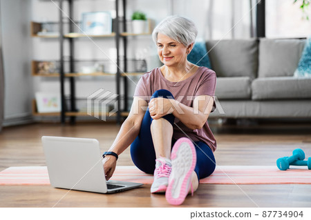 happy woman with laptop exercising at home happy woman with laptop exercising at home 87734904