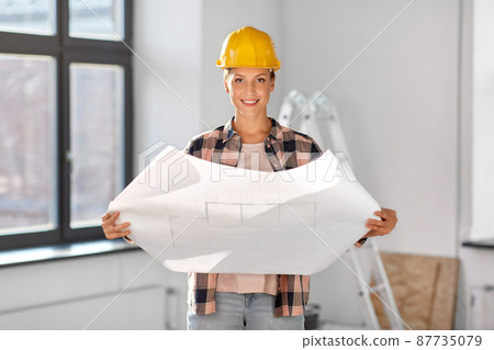 woman in helmet with blueprint at home woman in helmet with blueprint at home 87735079