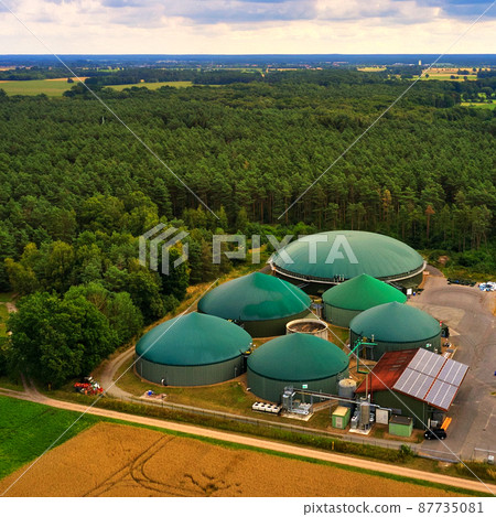 Aerial view of a biogas plant with silage piles and digesters for the production of methane gas 87735081
