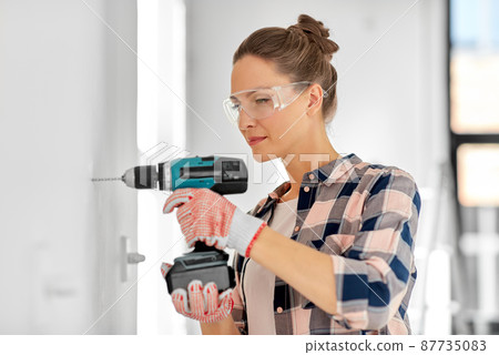 woman with perforator drilling wall at home woman with perforator drilling wall at home 87735083