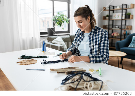 woman making or knotting macrame on table at home woman making or knotting macrame on table at home 87735263