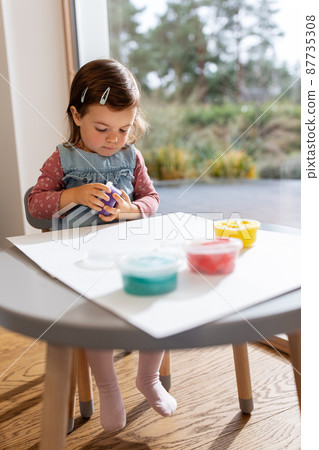 baby girl with modeling clay playing at home 87735308
